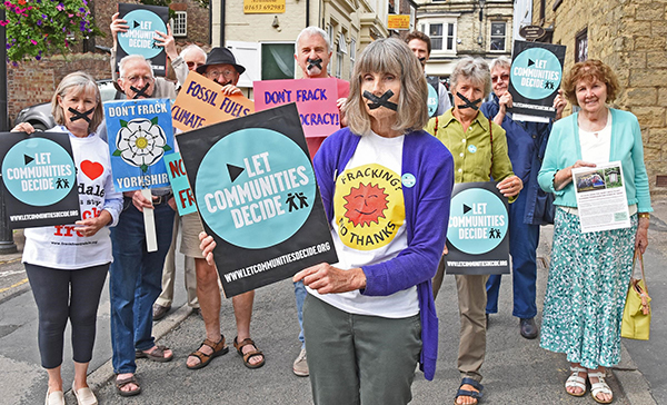 Eight elderly activists hold anti-fracking signs