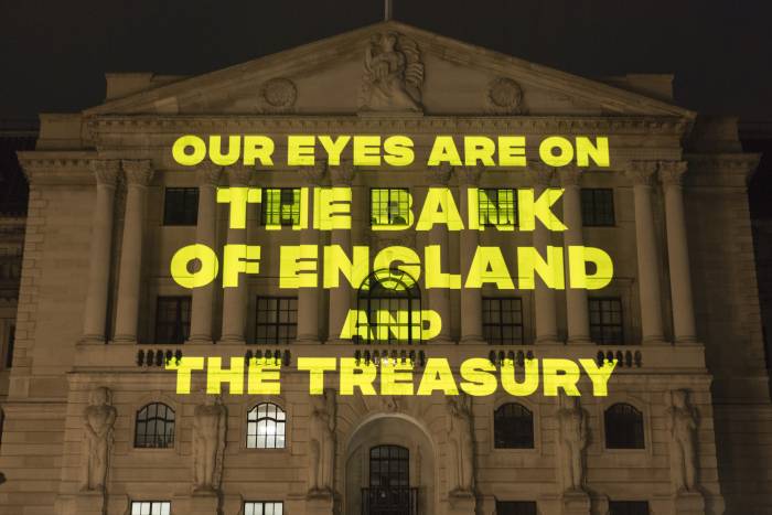 Yellow text reading "Our eyes are on the Bank of England and the Treasury' being projected onto the Bank of England at night-time